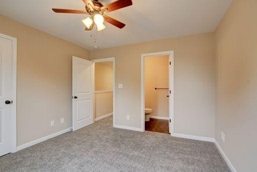 unfurnished bedroom featuring ceiling fan, light carpet, and ensuite bath