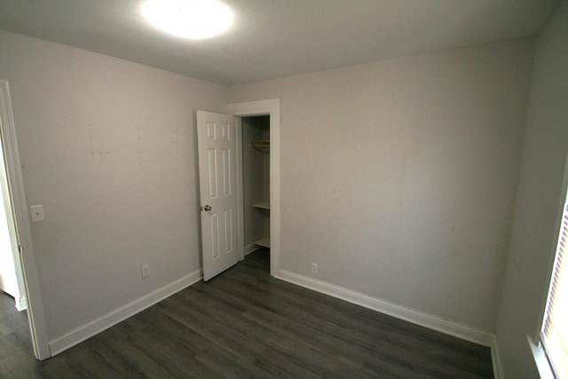 unfurnished room featuring baseboards and dark wood-style flooring