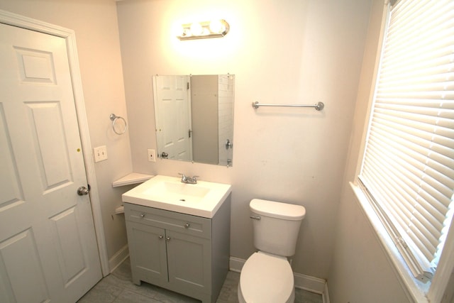 bathroom featuring plenty of natural light, vanity, toilet, and baseboards