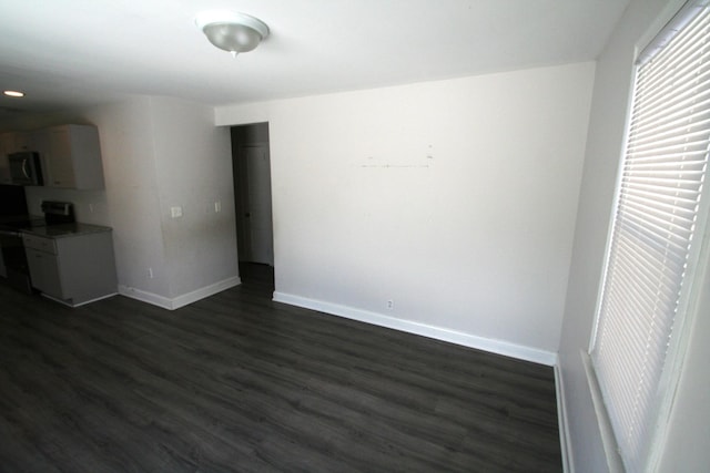 unfurnished living room with dark wood-style flooring and baseboards