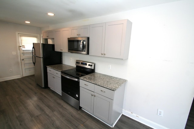 kitchen with light stone countertops, baseboards, dark wood-style floors, and appliances with stainless steel finishes