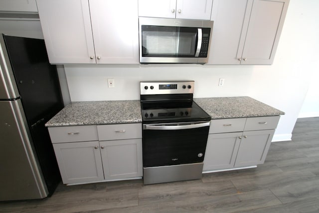 kitchen featuring stainless steel appliances, white cabinetry, and light stone countertops