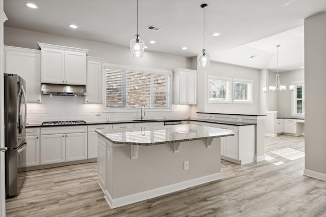 kitchen featuring stainless steel appliances, a center island, sink, and white cabinets