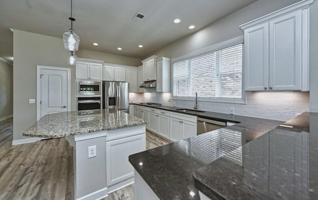 kitchen with white cabinetry, stainless steel appliances, decorative light fixtures, and sink