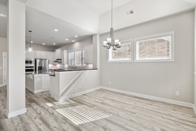 kitchen with sink, appliances with stainless steel finishes, white cabinetry, light hardwood / wood-style floors, and decorative light fixtures