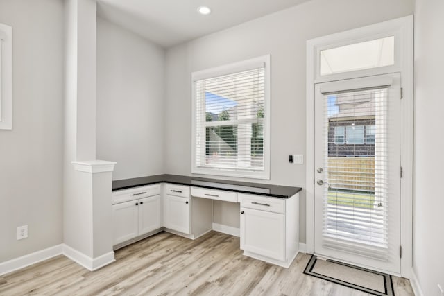 unfurnished office featuring built in desk and light hardwood / wood-style flooring