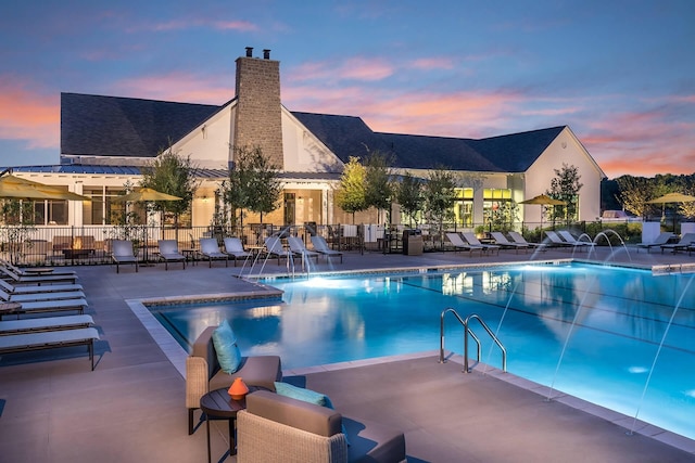 pool at dusk with a patio area