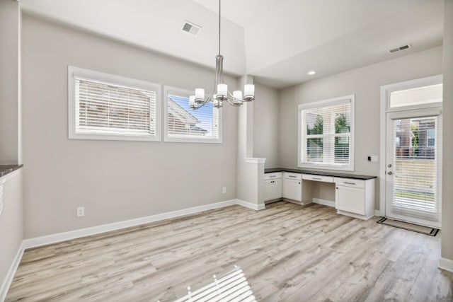 unfurnished dining area with an inviting chandelier and light hardwood / wood-style floors