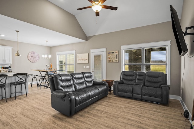 living room with lofted ceiling, ceiling fan with notable chandelier, and light hardwood / wood-style floors