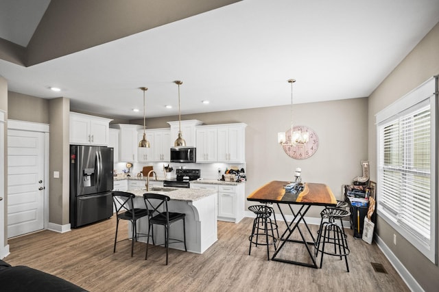 kitchen with hanging light fixtures, white cabinetry, appliances with stainless steel finishes, and sink