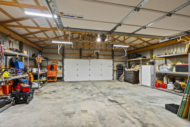 garage with a garage door opener, a workshop area, and white fridge