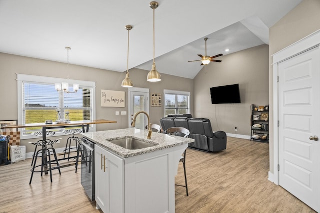 kitchen with sink, dishwasher, white cabinetry, light stone counters, and a center island with sink