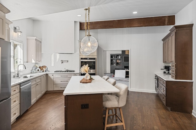 kitchen featuring sink, a breakfast bar area, hanging light fixtures, appliances with stainless steel finishes, and beamed ceiling