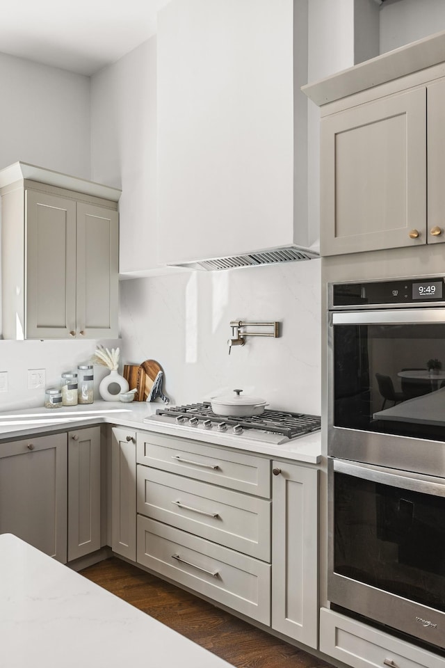 kitchen featuring dark wood-type flooring, stainless steel appliances, and wall chimney exhaust hood