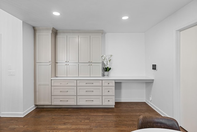 office with built in desk and dark hardwood / wood-style floors