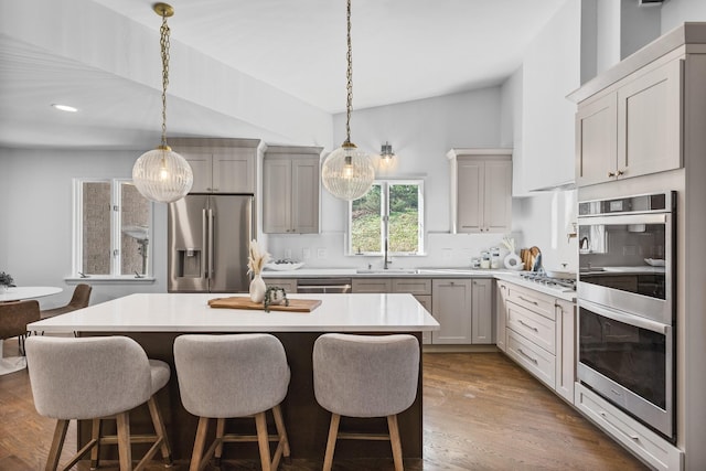 kitchen with dark hardwood / wood-style flooring, hanging light fixtures, stainless steel appliances, and a center island