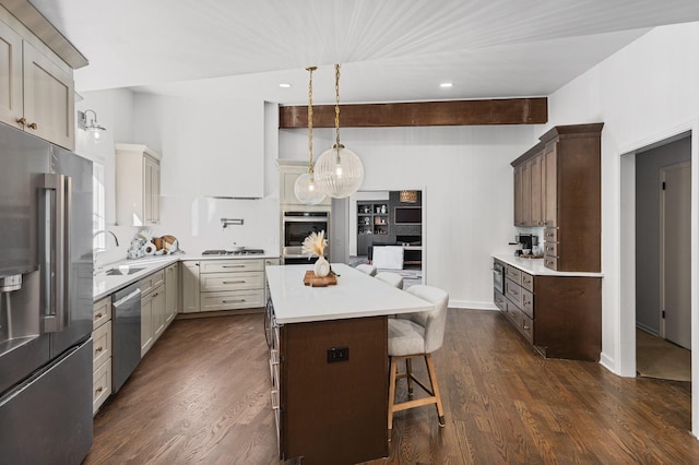 kitchen with a kitchen island, appliances with stainless steel finishes, sink, a kitchen breakfast bar, and cream cabinets