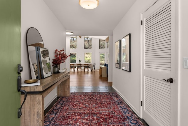 hall featuring baseboards and dark tile patterned flooring