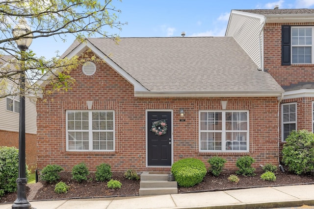 traditional-style home featuring brick siding and a shingled roof