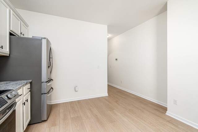 kitchen with light wood-style flooring, white cabinetry, stainless steel appliances, and baseboards