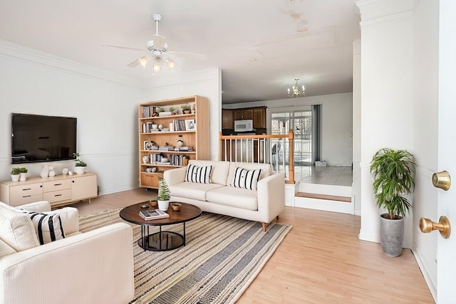 living area with light wood-type flooring, ornamental molding, and a ceiling fan