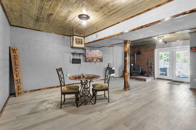 dining space featuring a wood stove, heating unit, wooden ceiling, and light wood-type flooring