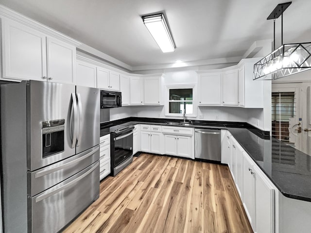 kitchen with white cabinetry, hanging light fixtures, light hardwood / wood-style flooring, and stainless steel appliances