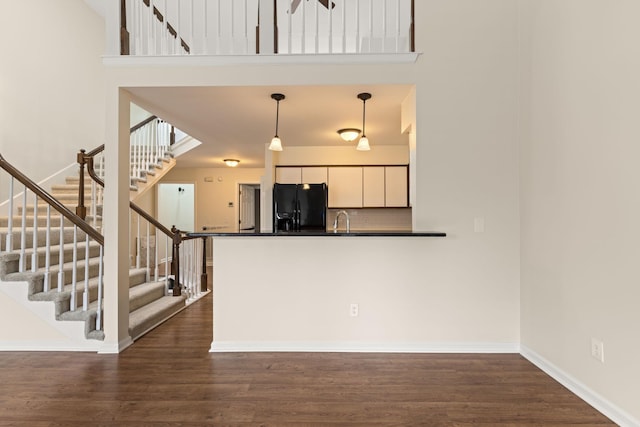 kitchen with white cabinetry, black fridge with ice dispenser, dark wood-type flooring, and decorative light fixtures