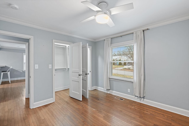 unfurnished bedroom featuring crown molding, ceiling fan, light hardwood / wood-style floors, and a closet