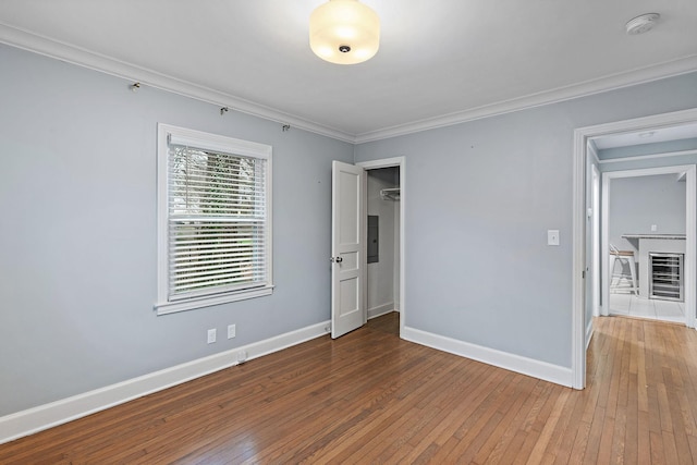 spare room with ornamental molding, electric panel, and hardwood / wood-style floors