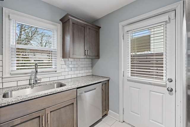 kitchen with sink, light tile patterned floors, dishwasher, light stone counters, and tasteful backsplash