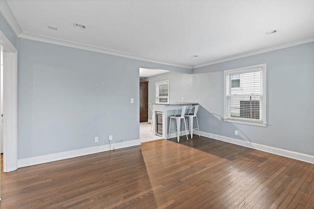 unfurnished room with hardwood / wood-style floors, a wealth of natural light, and ornamental molding