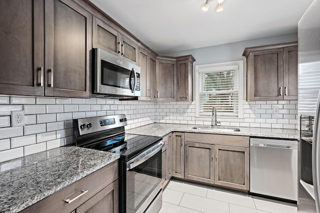 kitchen with sink, decorative backsplash, light stone countertops, and appliances with stainless steel finishes