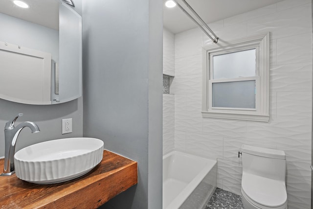 full bathroom with sink, tile walls, shower / bathing tub combination, and toilet