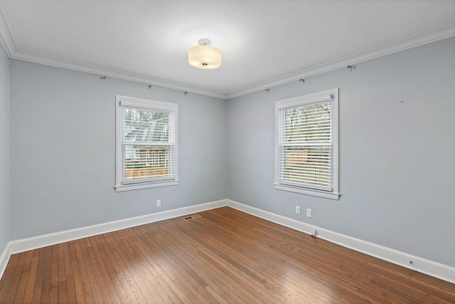 spare room featuring crown molding, a wealth of natural light, and wood-type flooring