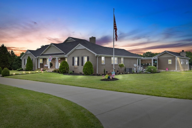 view of front of property featuring central AC and a lawn