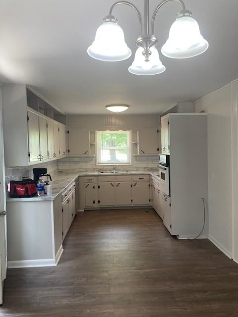 kitchen featuring tasteful backsplash, hanging light fixtures, sink, and white cabinets