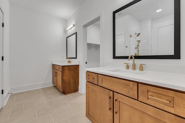 full bathroom with two vanities, a sink, a shower stall, and baseboards