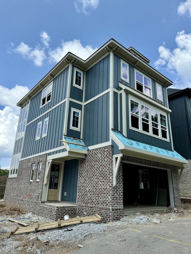 view of front of house featuring brick siding, board and batten siding, and an attached garage