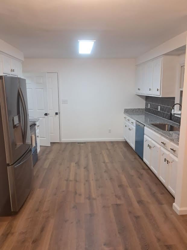 kitchen featuring appliances with stainless steel finishes, white cabinets, stone counters, dark hardwood / wood-style flooring, and sink