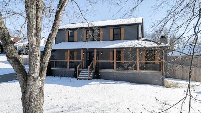 view of front facade featuring covered porch and a chimney