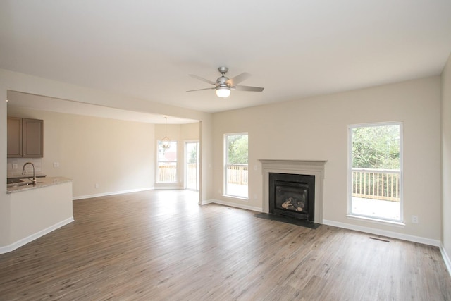 unfurnished living room with ceiling fan, sink, and light hardwood / wood-style flooring