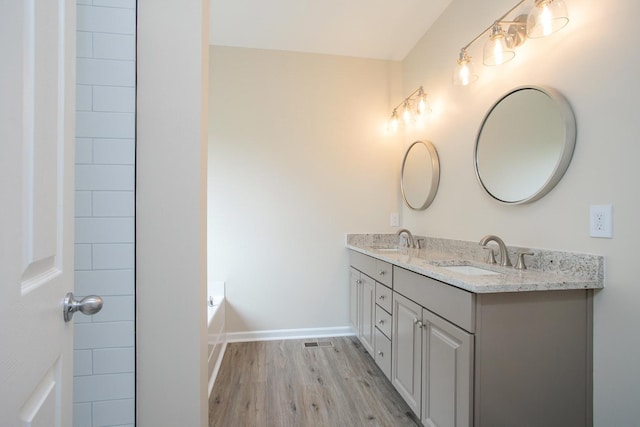 bathroom featuring wood-type flooring, vanity, and a washtub