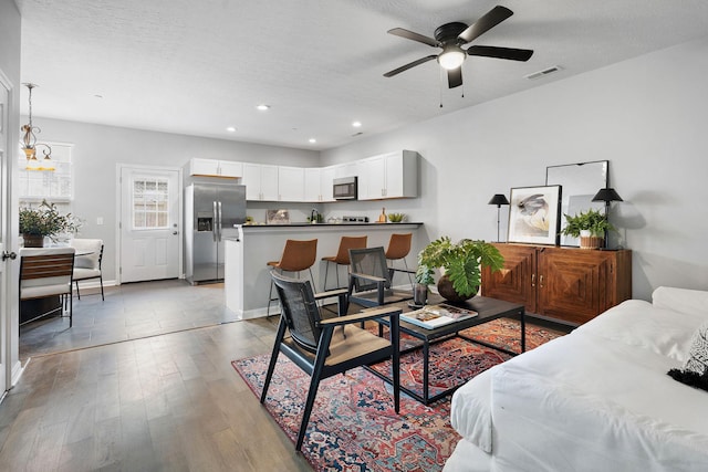 living area featuring dark wood finished floors, recessed lighting, visible vents, a textured ceiling, and baseboards