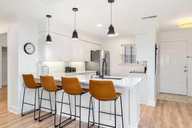 kitchen with white cabinetry, pendant lighting, stainless steel fridge, and kitchen peninsula