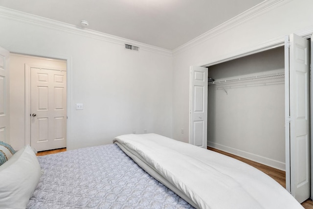 bedroom featuring ornamental molding, hardwood / wood-style floors, and a closet