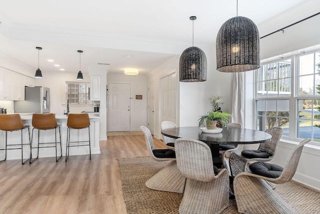 dining area with crown molding, plenty of natural light, and light hardwood / wood-style floors