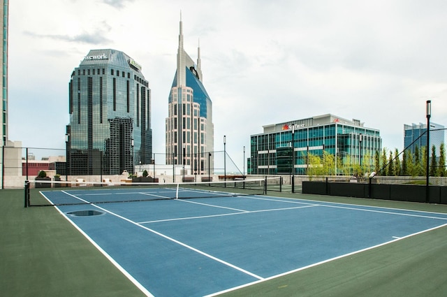 view of sport court with a city view and fence