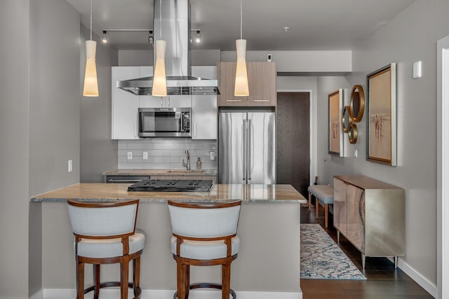 kitchen with a kitchen bar, dark wood finished floors, stainless steel appliances, island range hood, and decorative backsplash