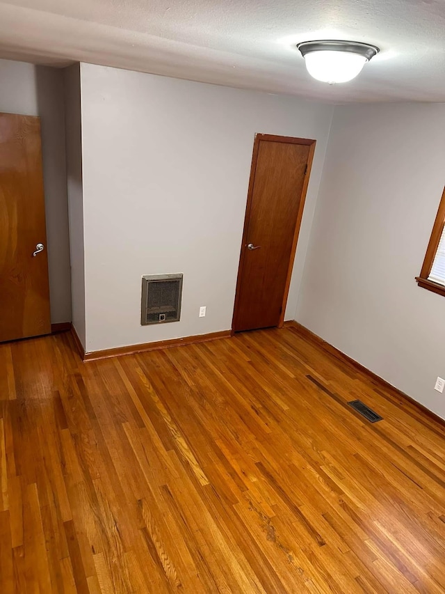 unfurnished room featuring light hardwood / wood-style floors and heating unit